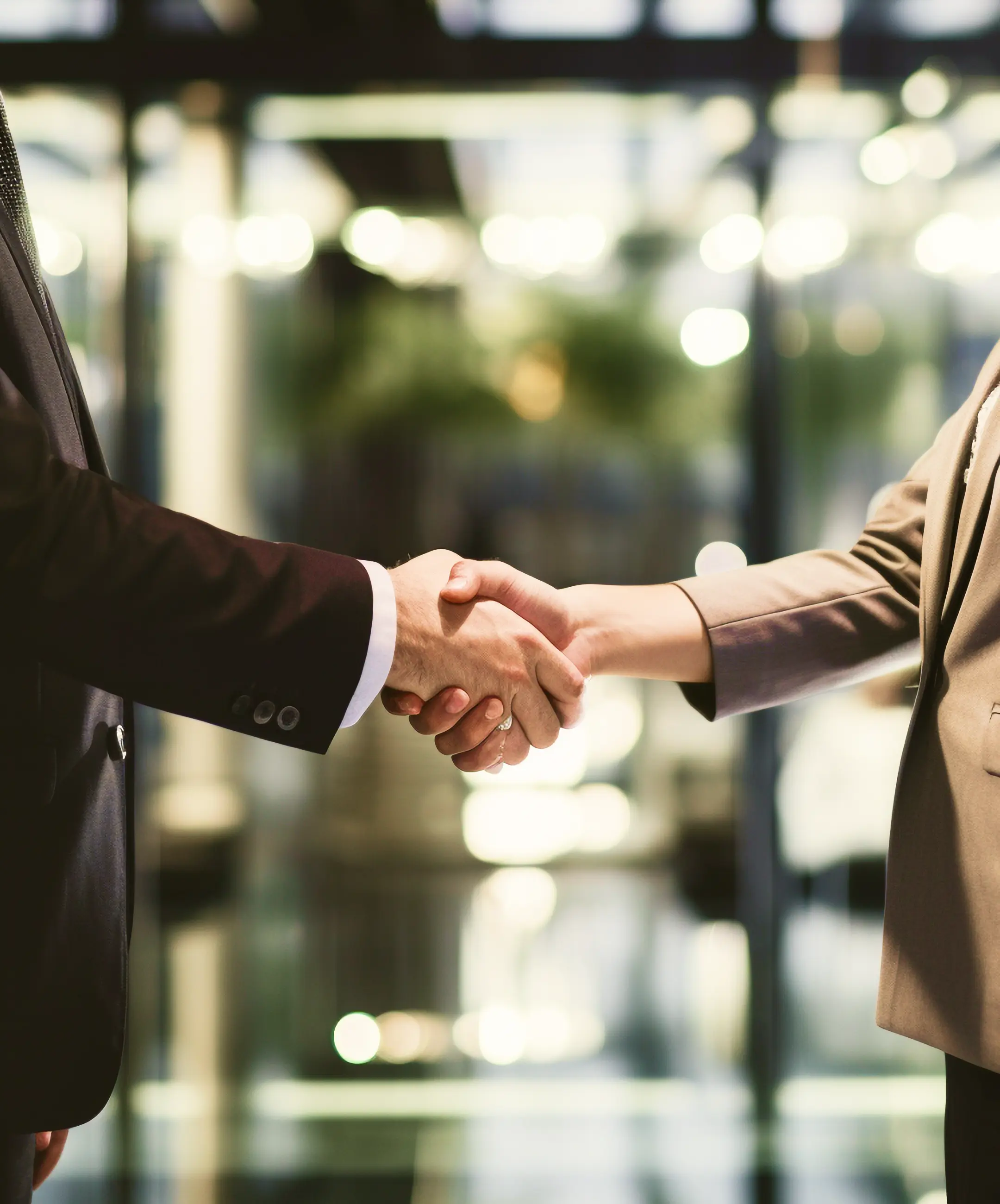 Two business professionals shake hands after a successful mergers and acquisitions agreement