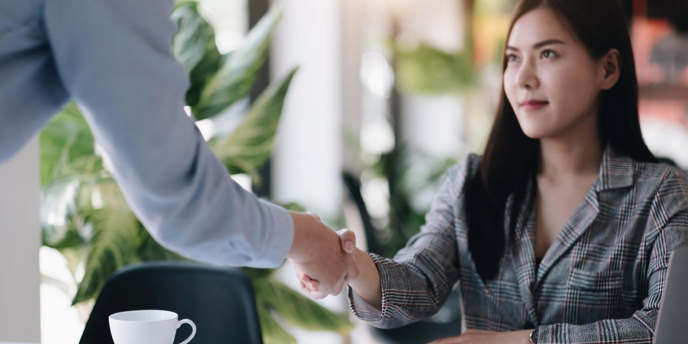 Business buyer shakes hands with seller after negotiating earn-out terms